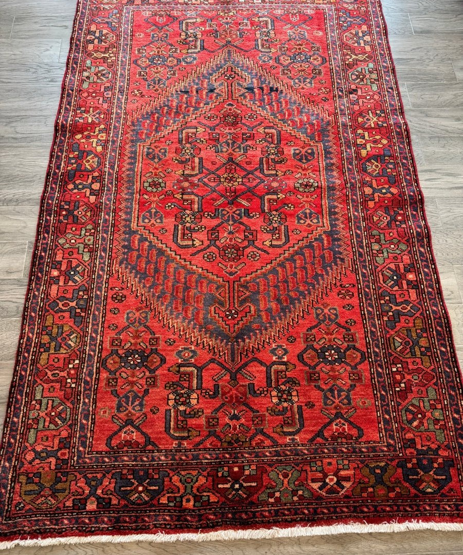 Red Persian-style rug with ornate central medallion and wide repeating border