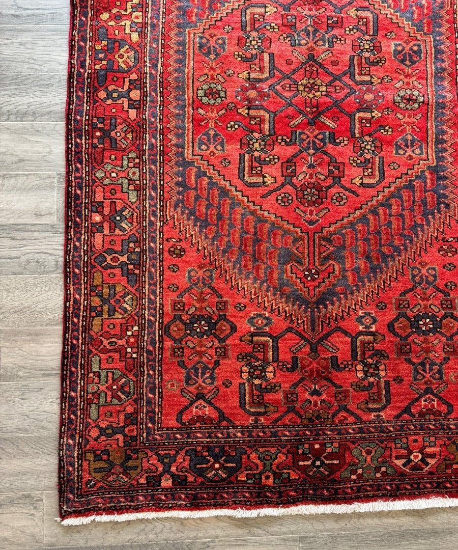 Red Persian-style rug corner with detailed medallion and geometric border