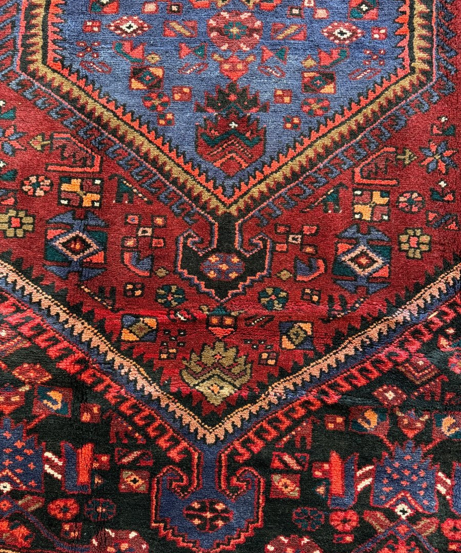 Red, navy, and teal geometric rug pattern with multicolor diamond accents.