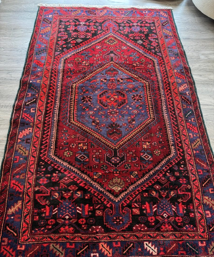 Rug with red field, navy geometric medallion, and blue-accented border.