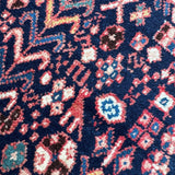 Geometric pattern rug with navy background and red, cream, turquoise accents