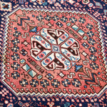 Persian-style rug close-up of rust medallion with navy, teal, and white details.