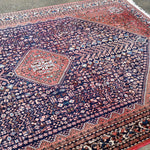Persian-style rug with navy center medallion and rust orange border details.
