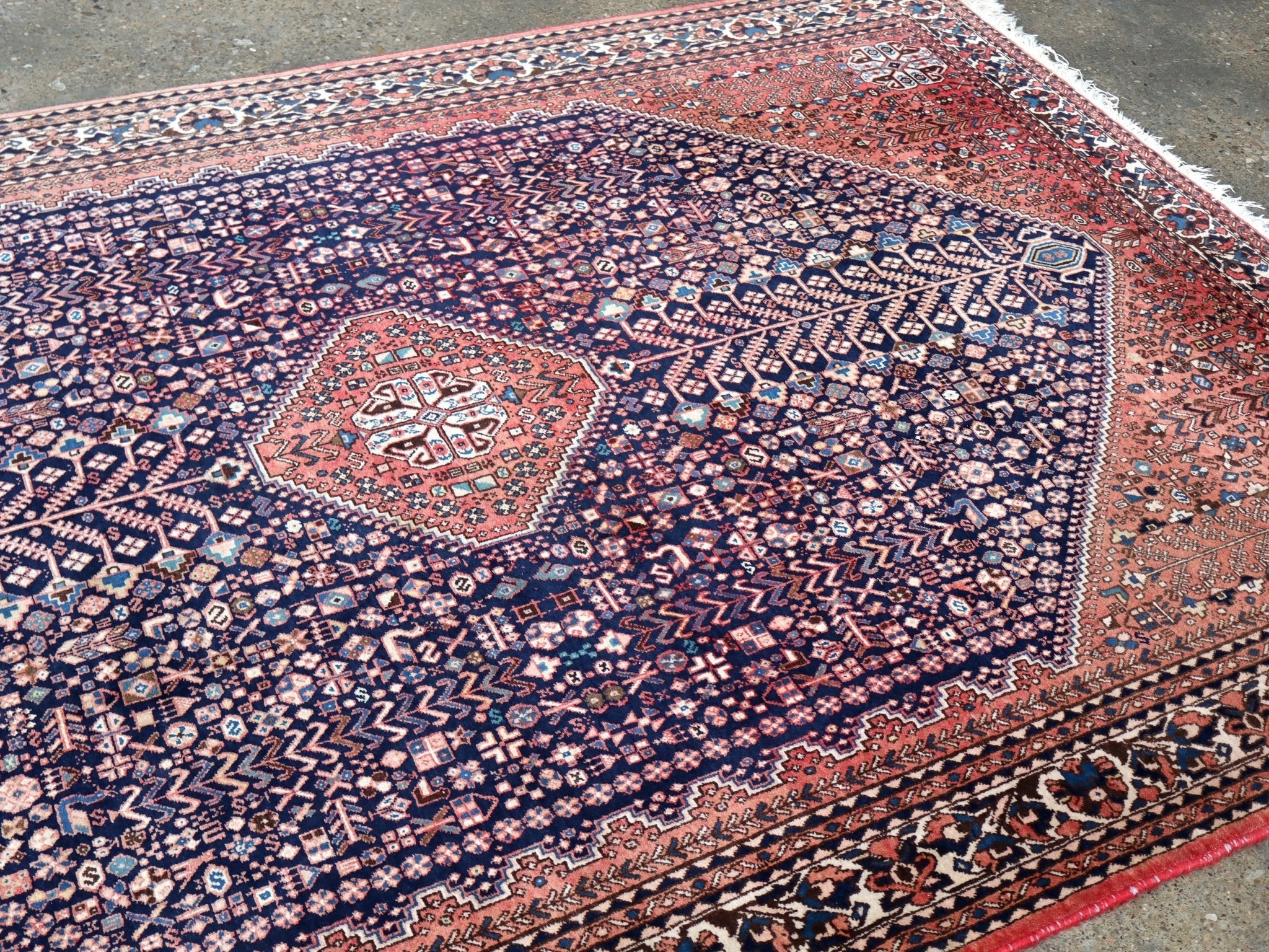 Persian-style rug with navy center medallion and rust orange border details.