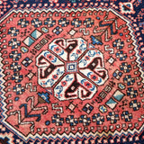 Persian-style area rug with rust red and navy geometric medallion pattern.
