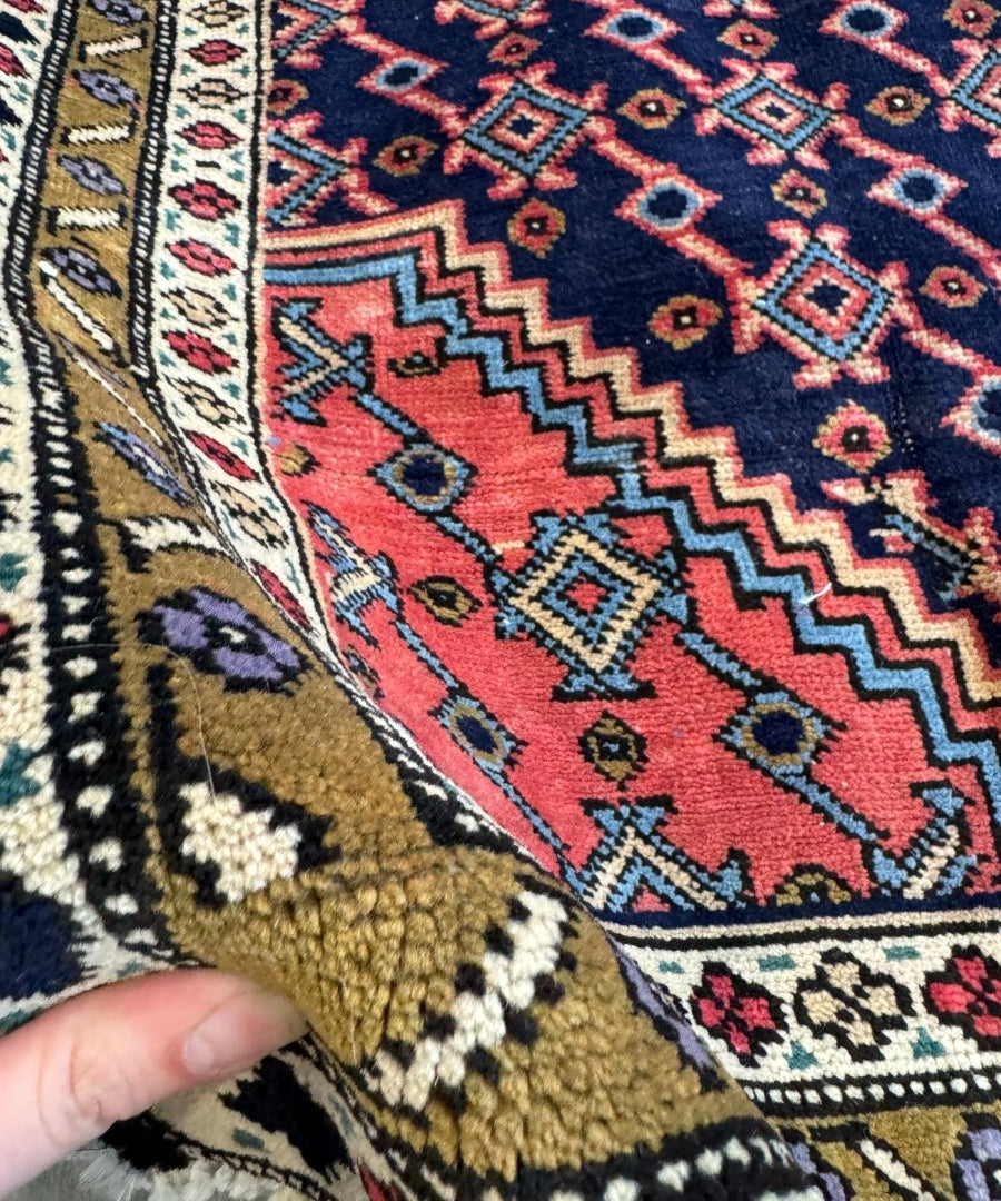 Close-up of Persian-style rug pile with red and navy chevron motifs and border trim