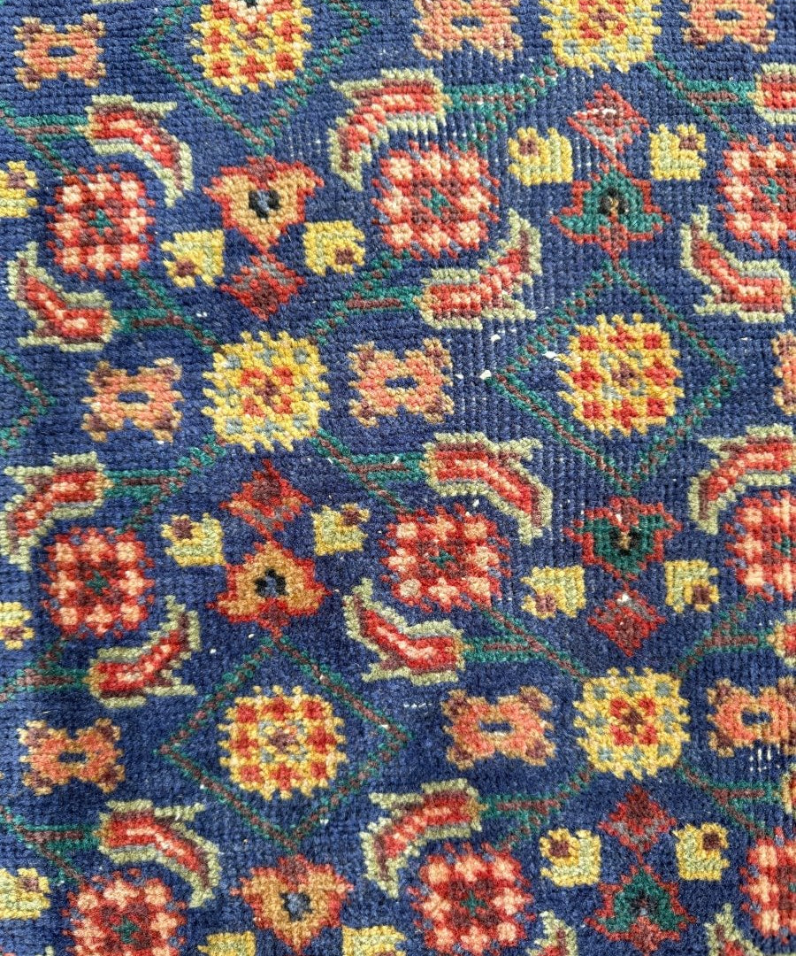 Close-up of blue Persian-style rug with multicolor floral and geometric motifs
