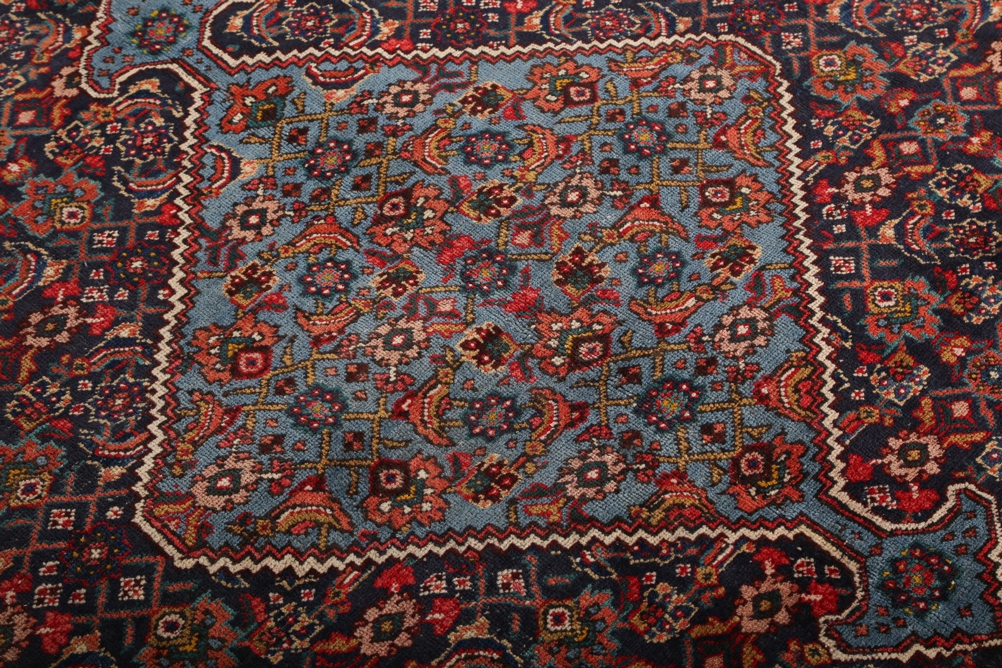 Persian rug top section with repeating medallions, diamonds, and warm red accents