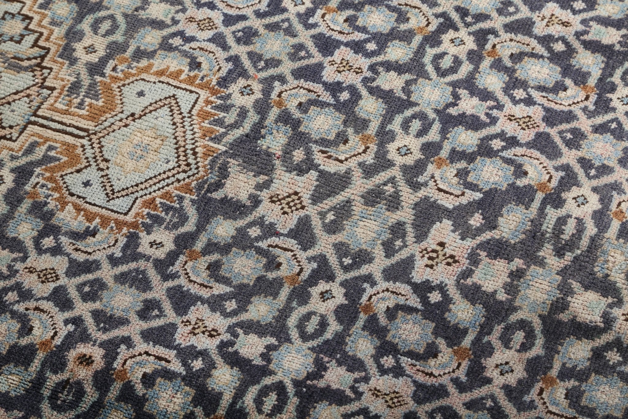 Woven rug pattern close-up with navy, blue, cream, and tan decorative icons