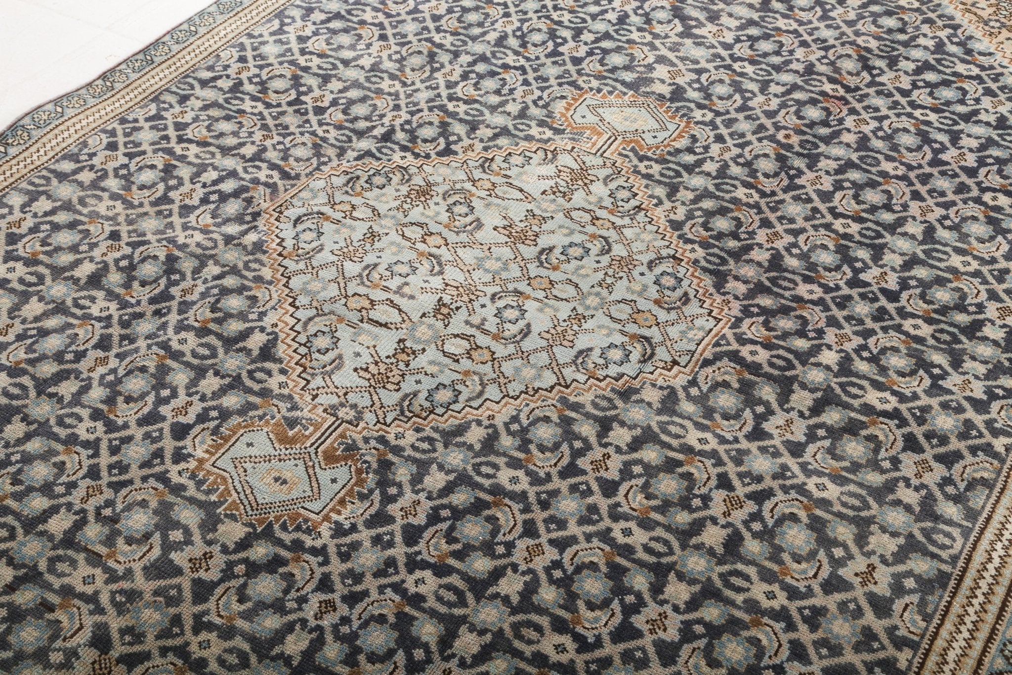 Persian-style area rug with central octagon medallion in cream and tan on blue