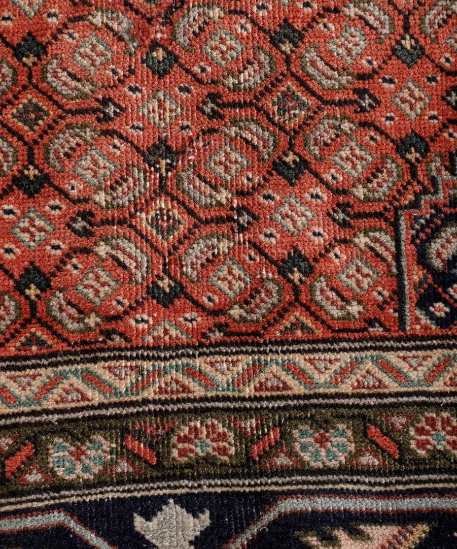 Persian Ardabil-style rug detail, rust scrolling patterns with navy accents and border
