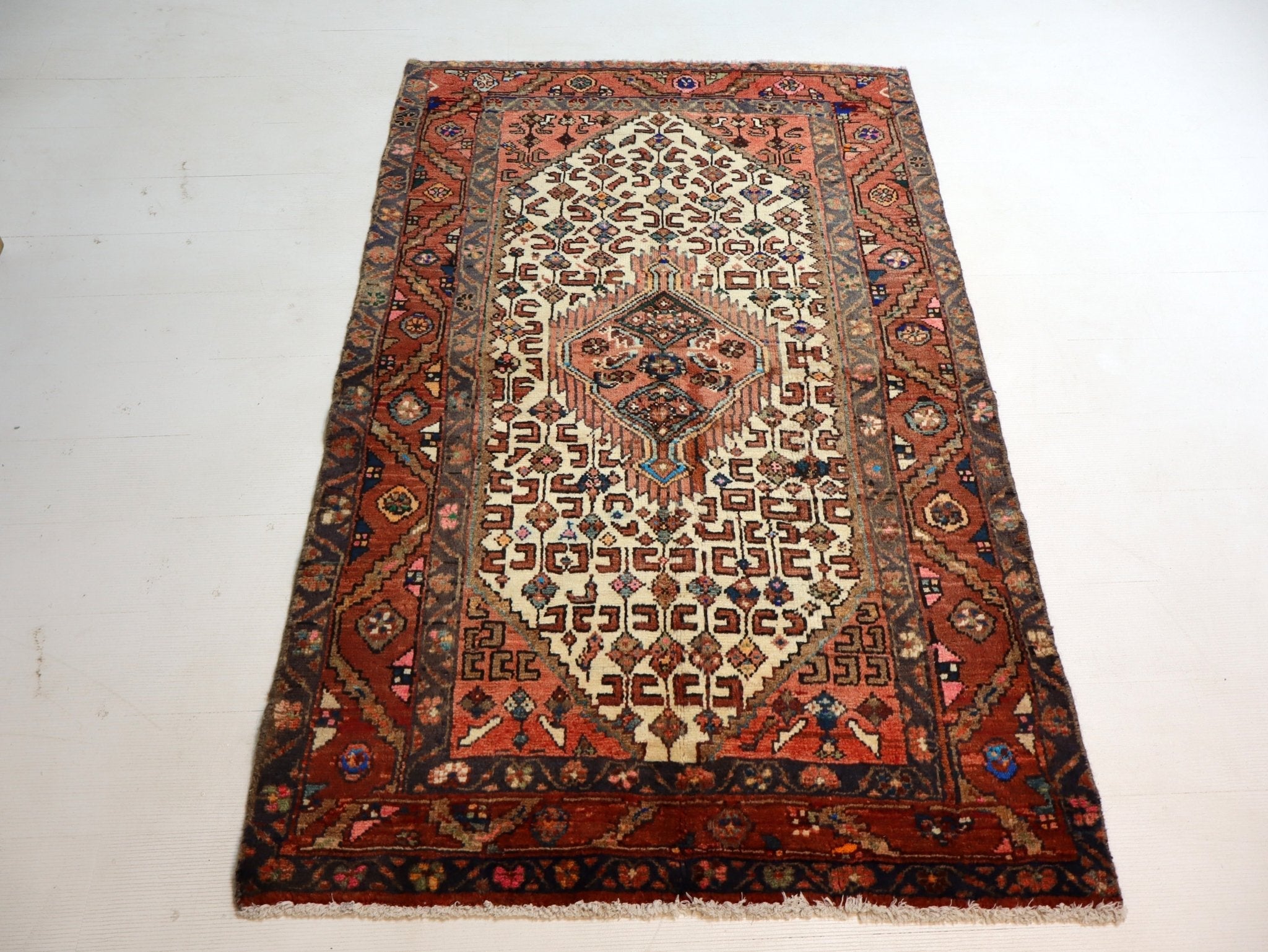 Persian-style area rug with rust, cream, and dark blue medallion pattern