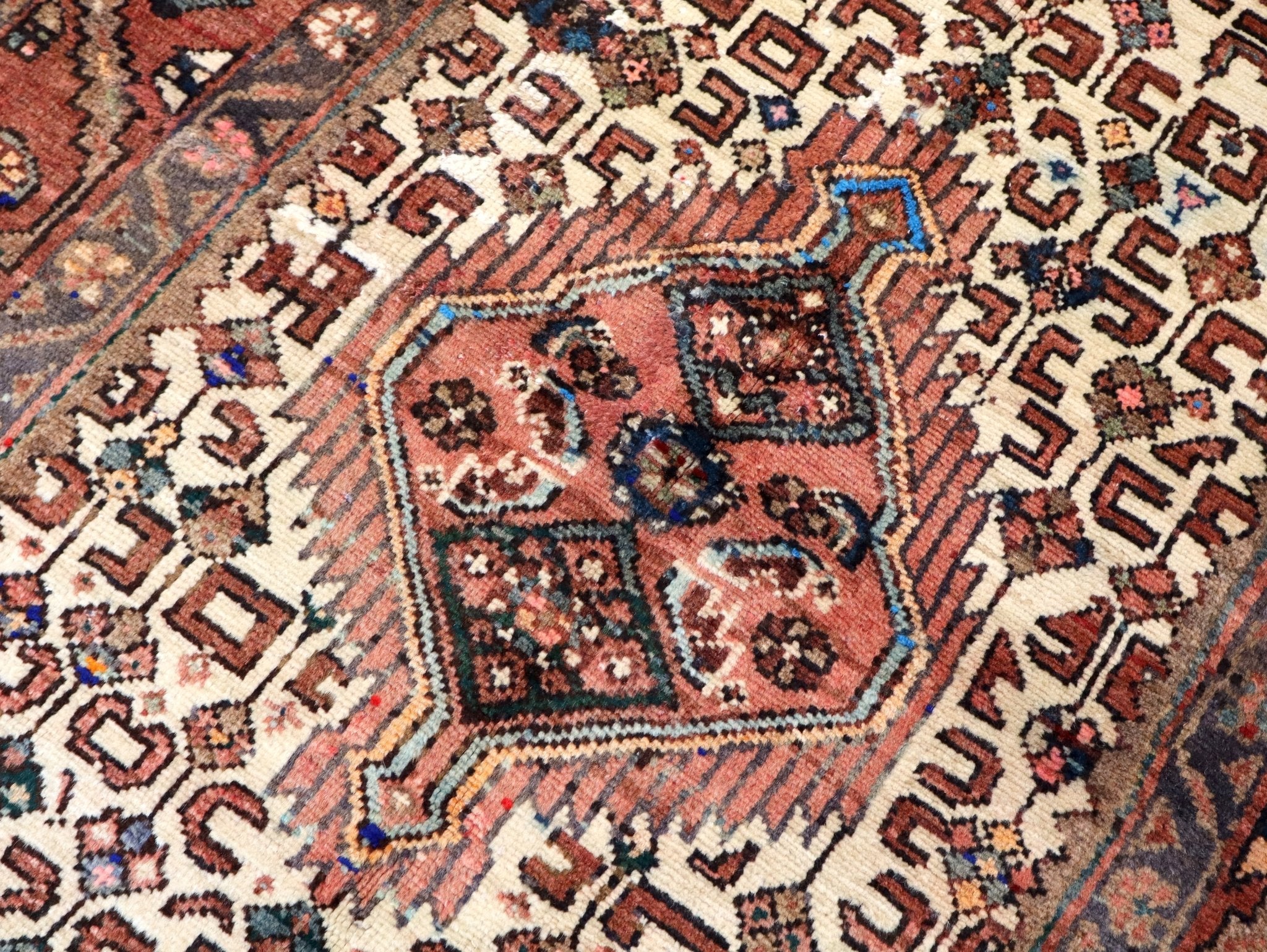 Rug pattern close-up with rust medallion, cream field, and blue diamond details