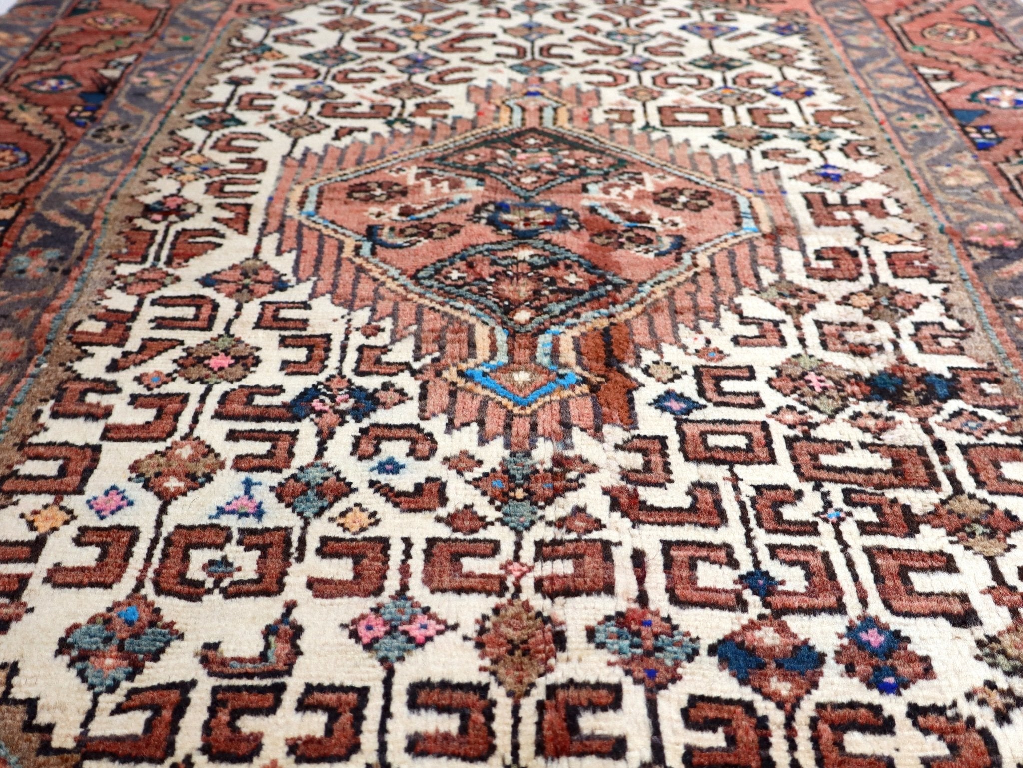 Close-up of rug center medallion with cream, rust, and blue geometric shapes