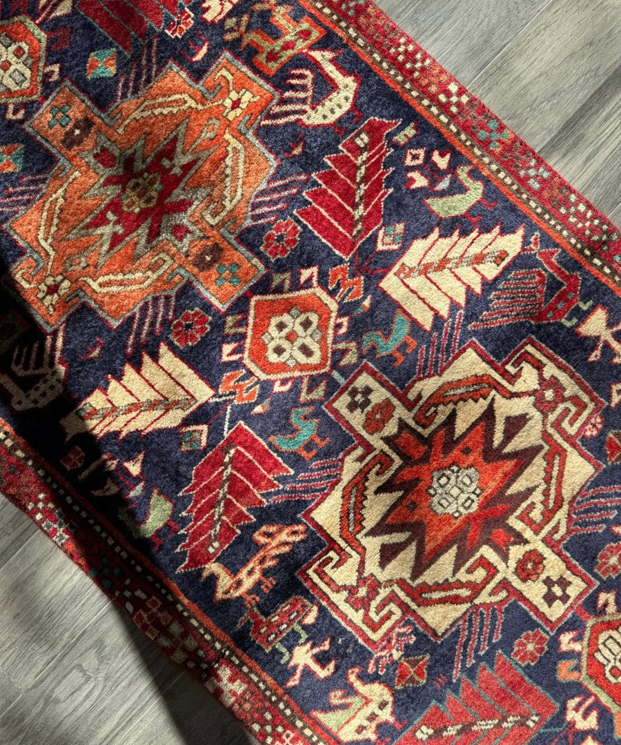 Close-up of navy runner rug with red border, multicolor geometric motifs and star shapes.