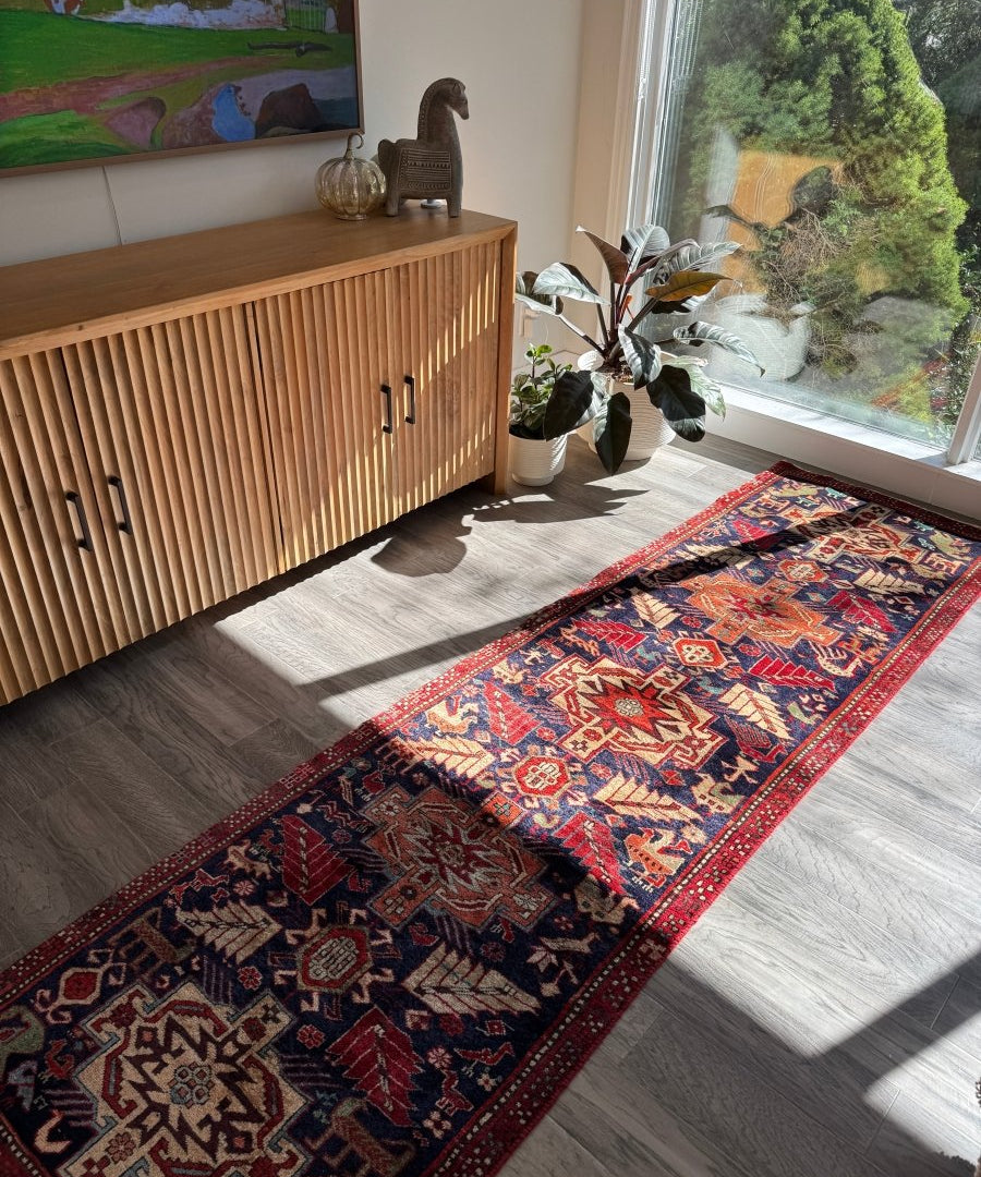 Red and navy patterned runner rug laid on light wood flooring in a living room setting.