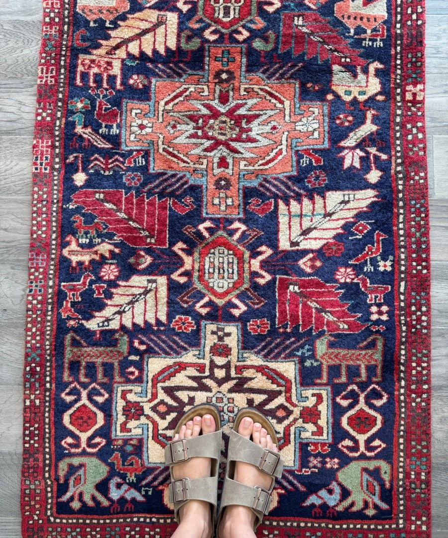 Runner rug with red border and navy field, geometric medallion and motifs in cream and blue.