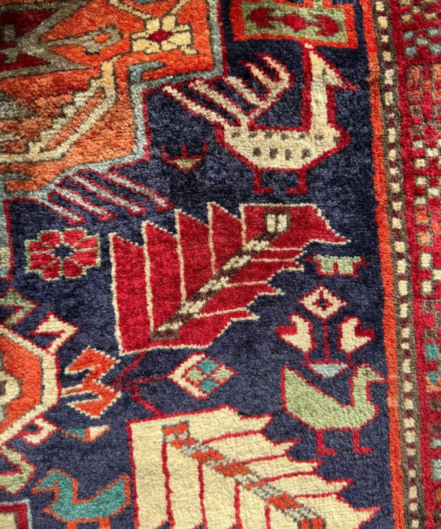 Detailed navy rug section with bold red shapes, cream accents, and repeating geometric patterns.