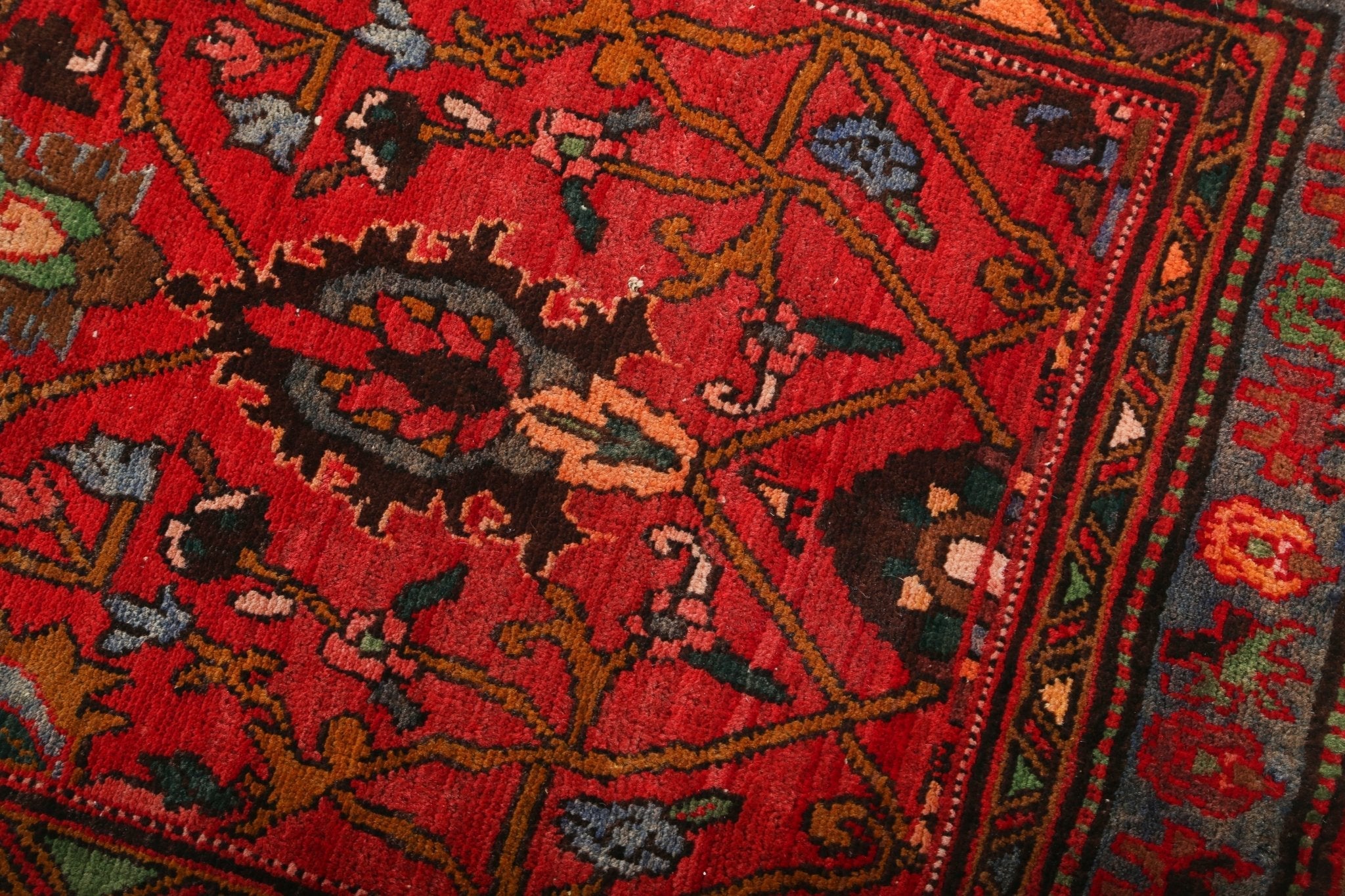 Red Persian-style runner rug with detailed medallion pattern and geometric border.