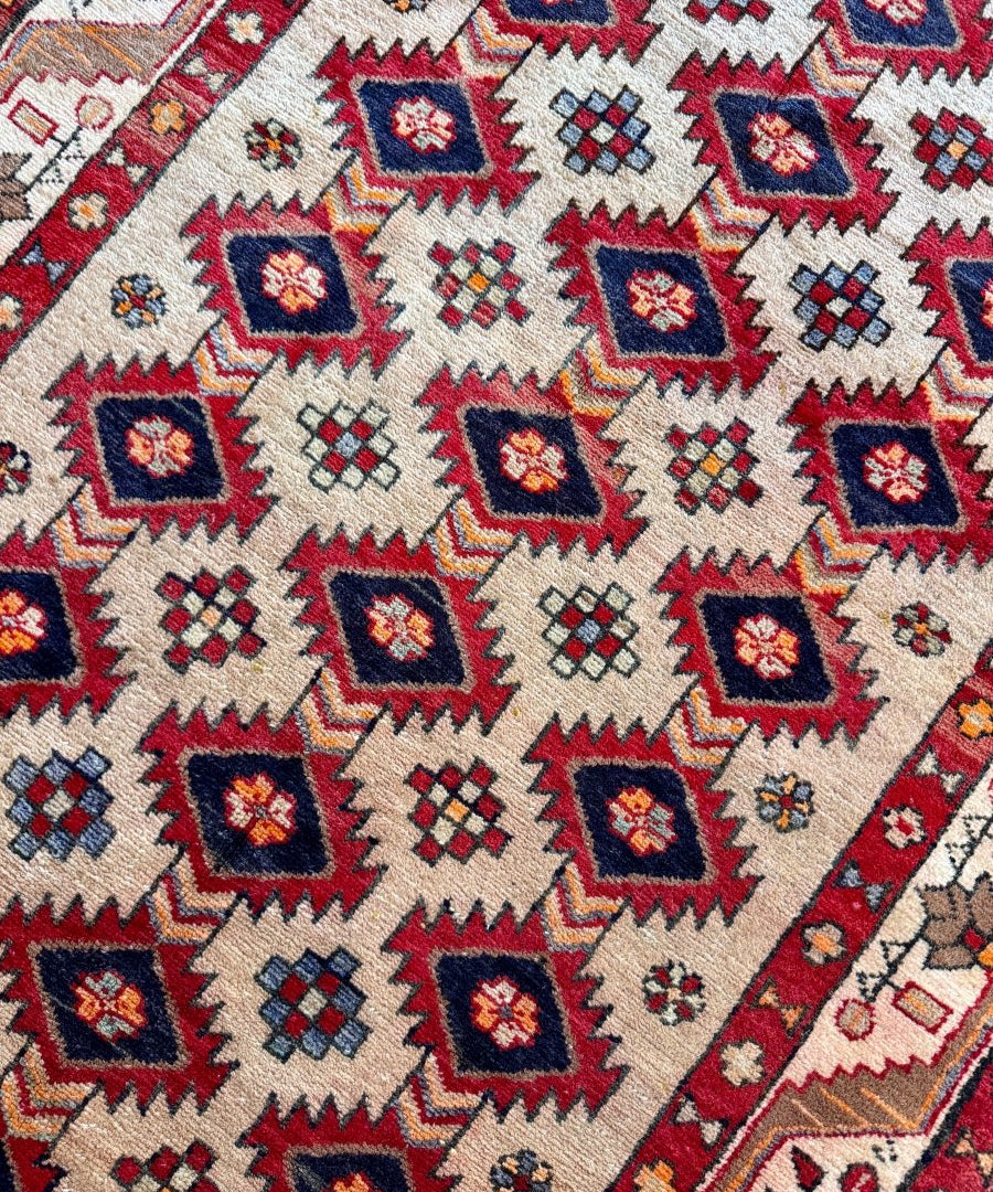 Close-up of Persian Azerbaijan runner rug: cream ground with red and navy diamond motifs