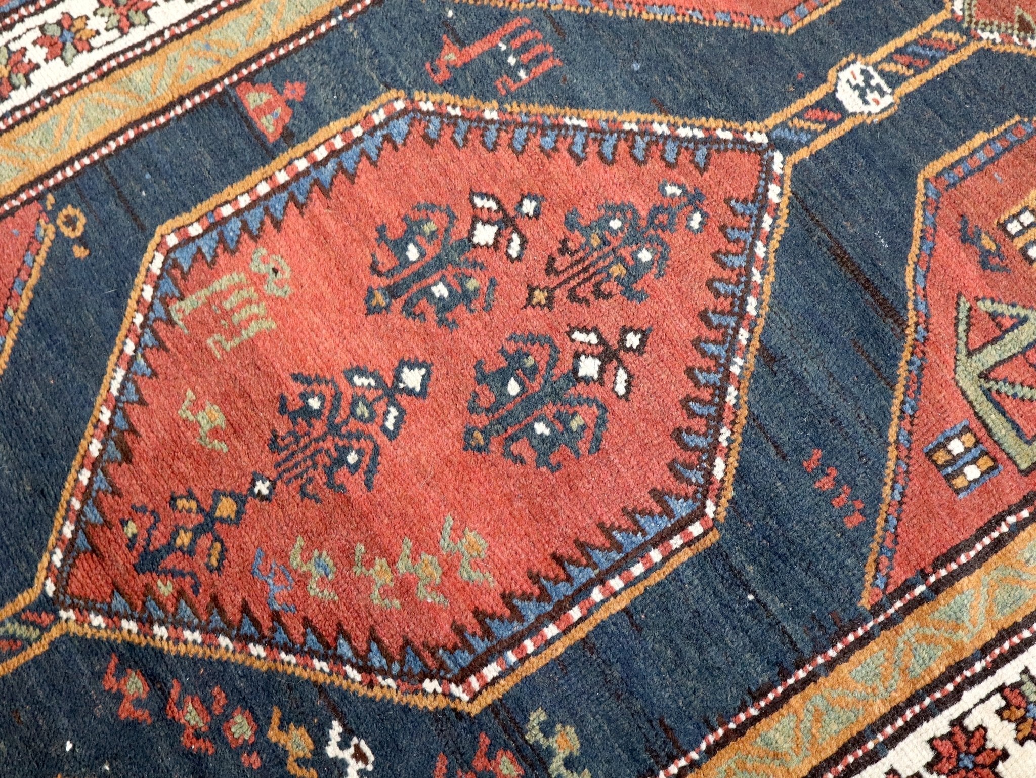 Persian runner rug close-up with rust red centerpiece and dark navy corner motifs