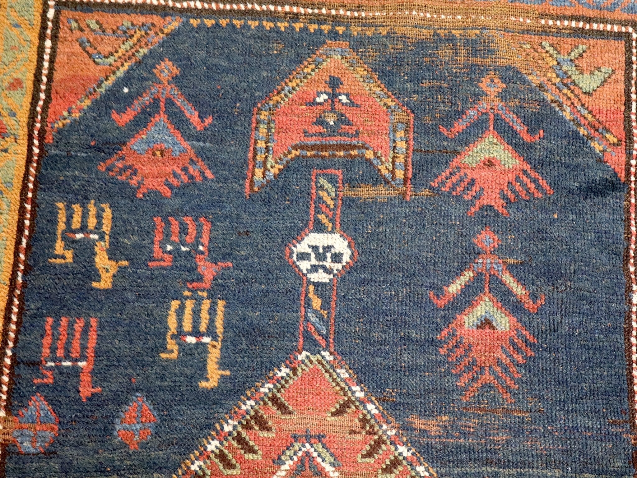Persian runner rug close-up, dark navy ground with rust motifs and woven texture