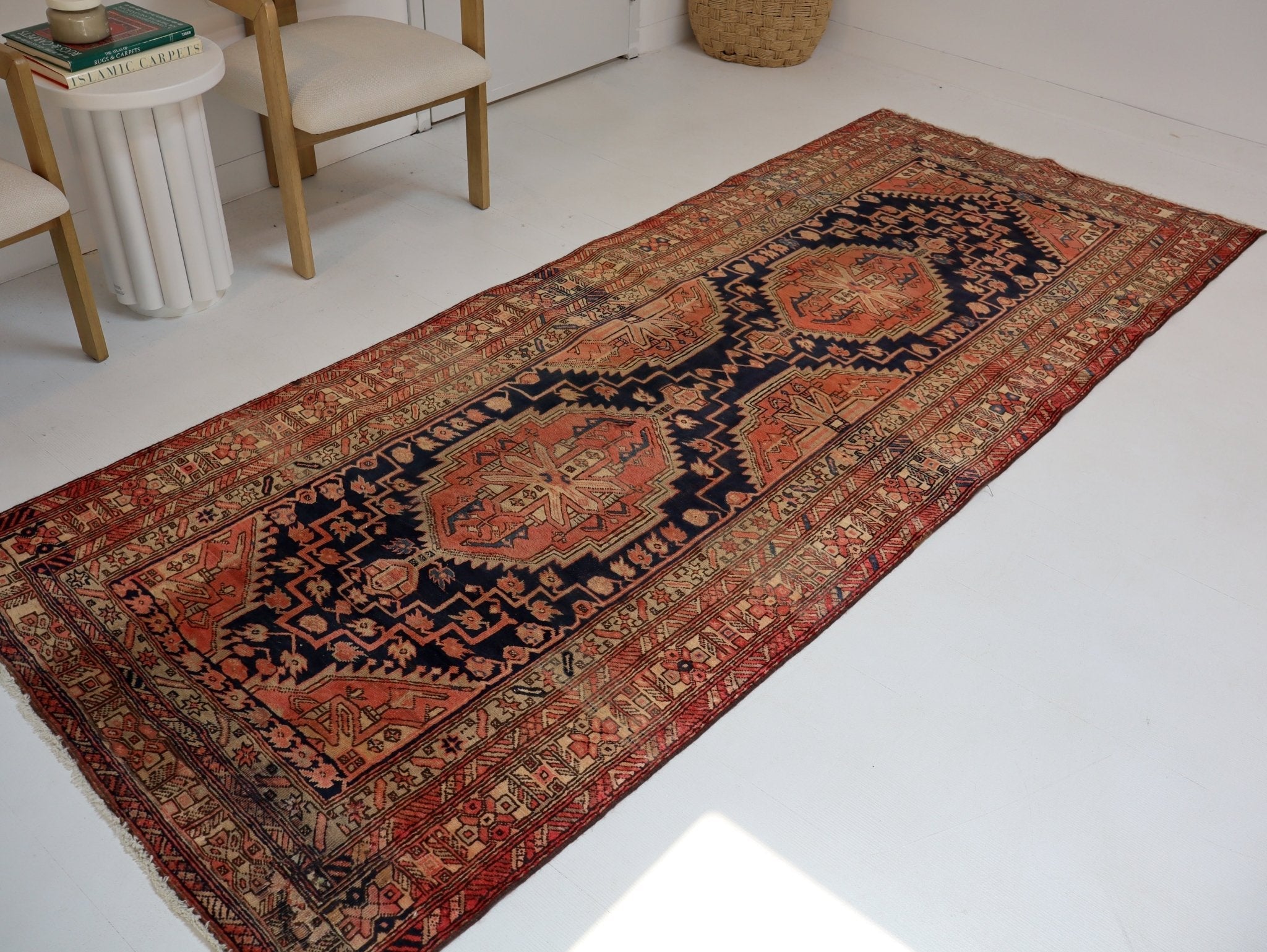 Persian Azerbaijani runner rug laid on white floor with red, navy, and tan medallions