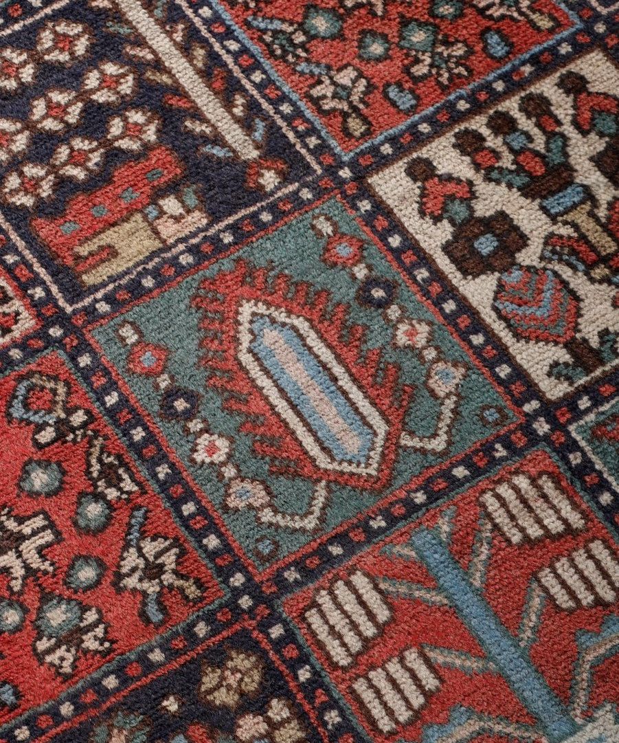 Close-up of Persian Bakhtiar rug pattern with red, blue, and ivory shapes and motifs.