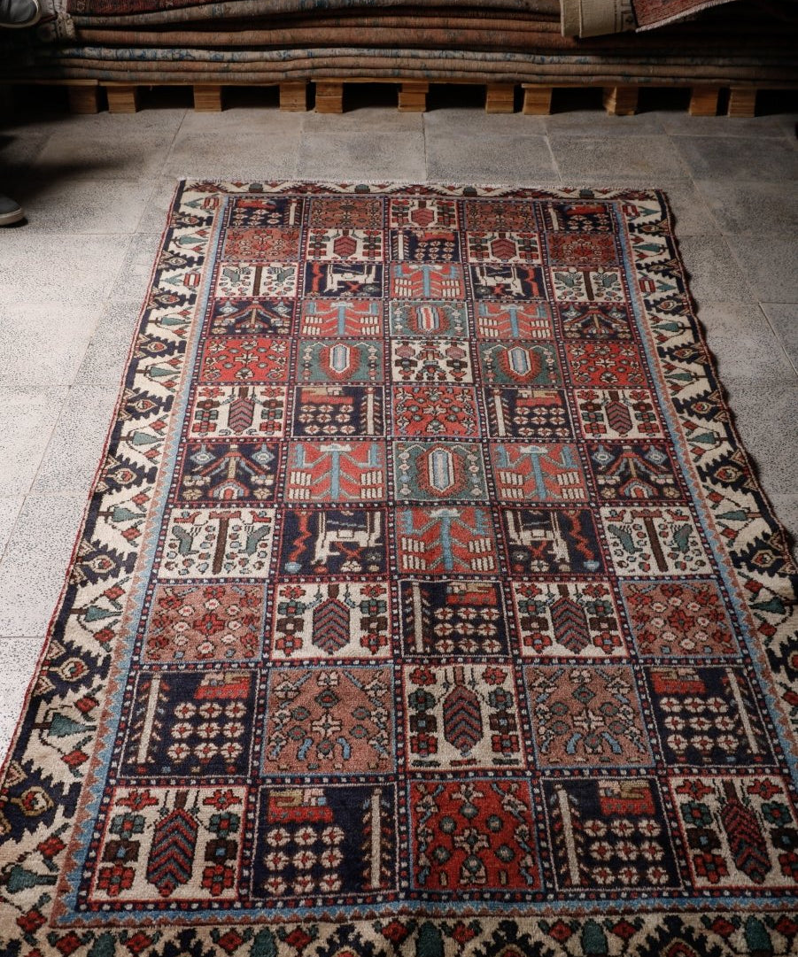Persian Bakhtiar rug laid flat on floor, showing red and navy geometric blocks.