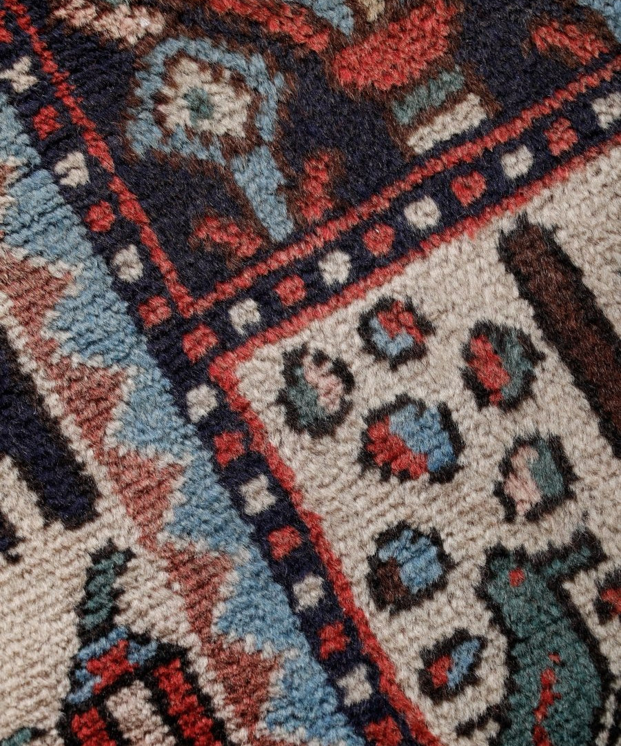 Close-up of Persian Bakhtiar rug border with red, navy, and light blue panel details.