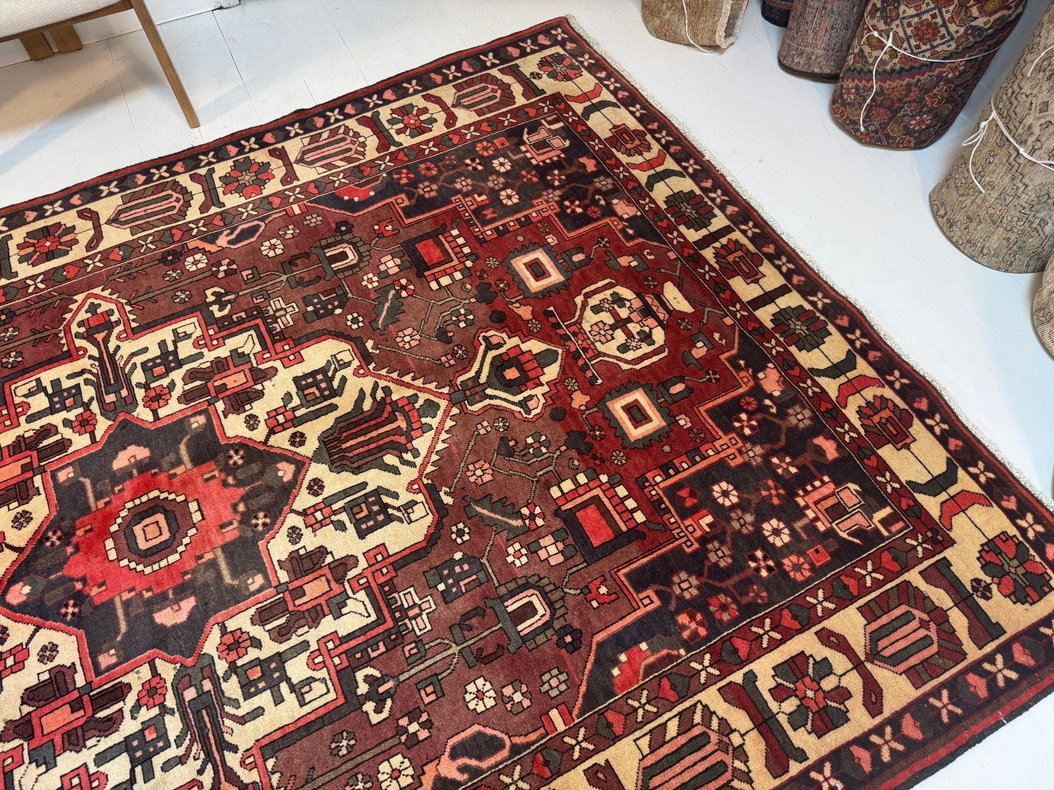 Persian Bakhtiar rug at an angle in a room, red field with cream accents and motifs