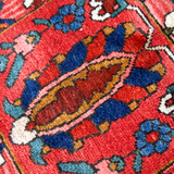Persian Bakhtiari rug close-up with red ground, blue accents, and ivory diamond details