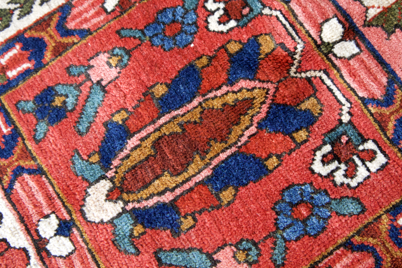 Persian Bakhtiari rug close-up with red ground, blue accents, and ivory diamond details