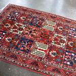 Persian Bakhtiari rug corner view with red border, blue panels, and multicolor motifs