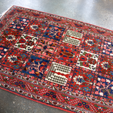 Persian Bakhtiari rug corner view with red border, blue panels, and multicolor motifs
