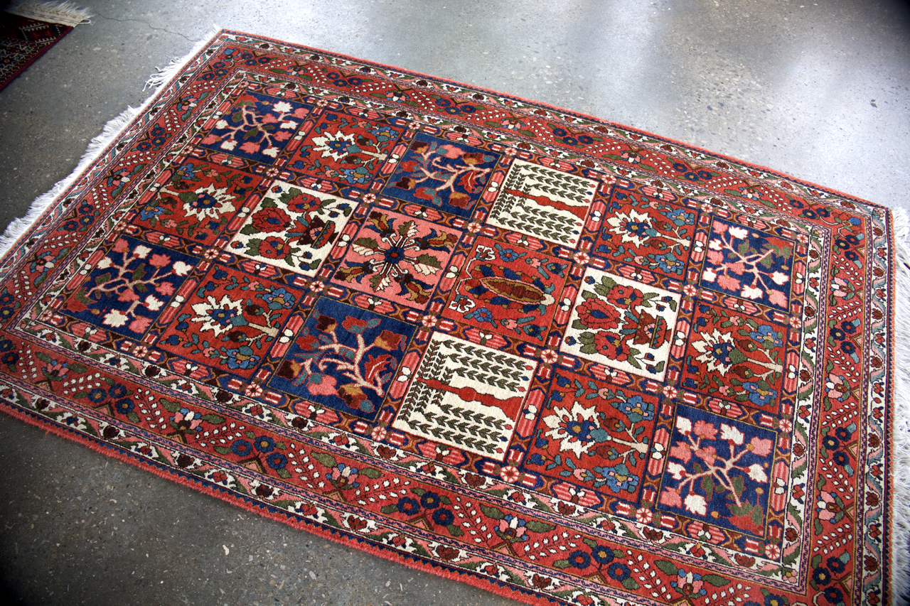 Persian Bakhtiari rug corner view with red border, blue panels, and multicolor motifs
