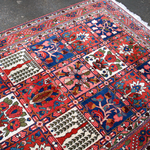 Persian Bakhtiari rug top view with red grid panels, floral motifs, and short fringes