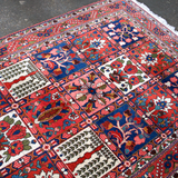 Persian Bakhtiari rug top view with red grid panels, floral motifs, and short fringes