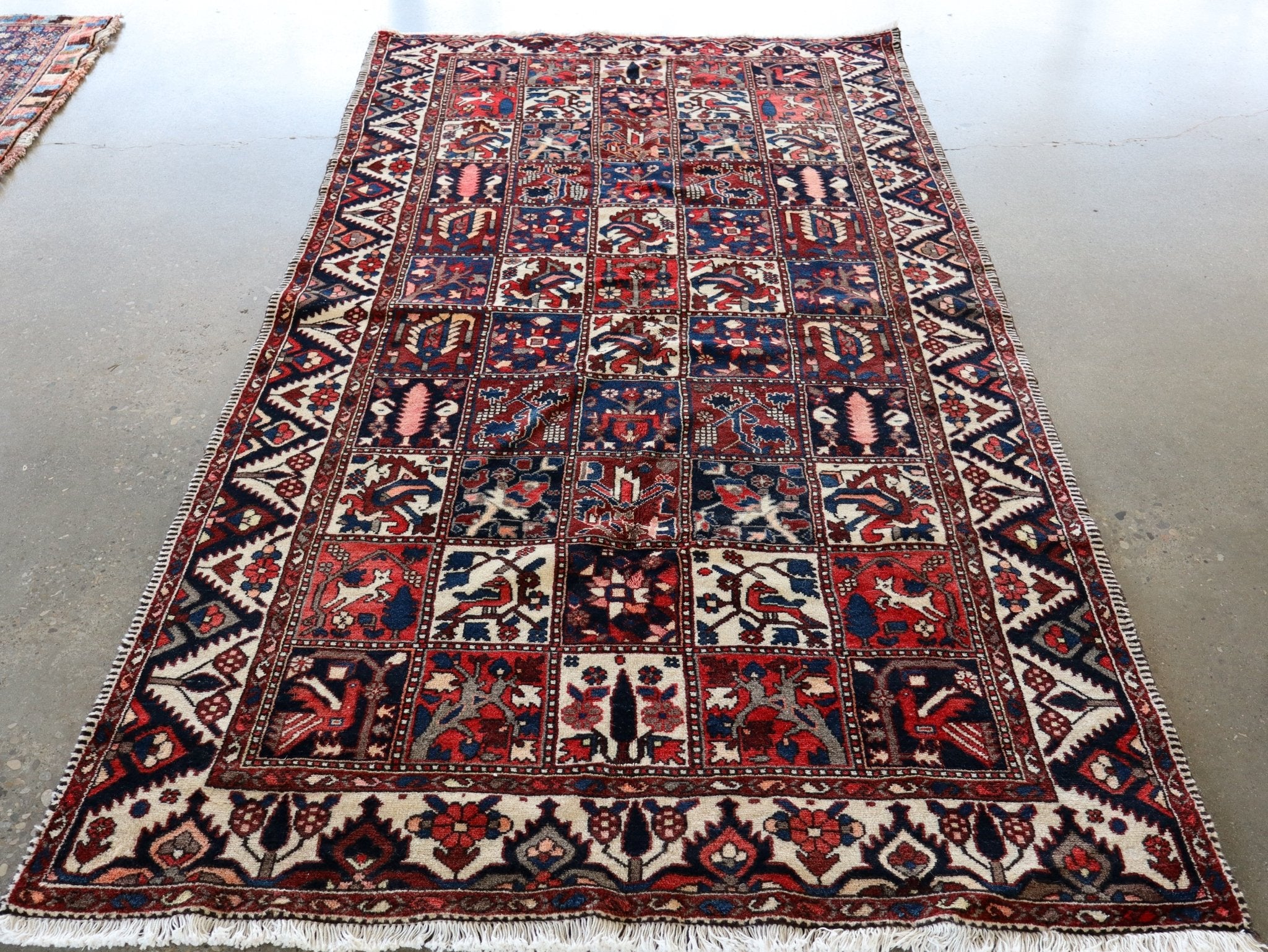 Persian rug with red and blue field, cream accents, and ornate geometric border