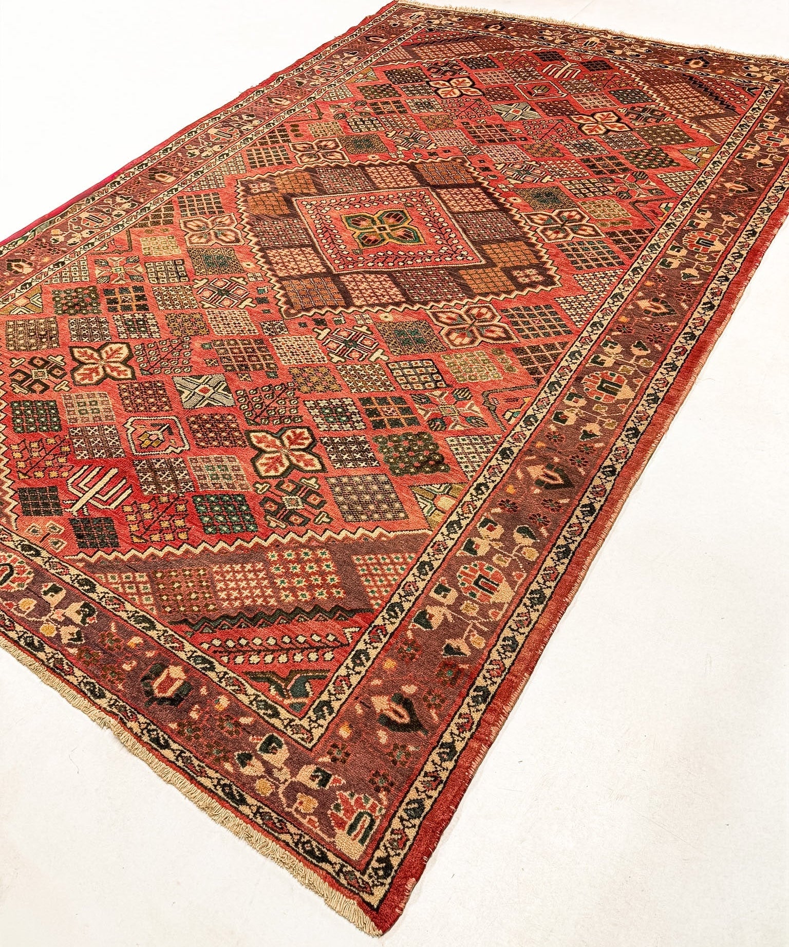 Persian Bakhtiari rug with red field, geometric medallion, and dark border