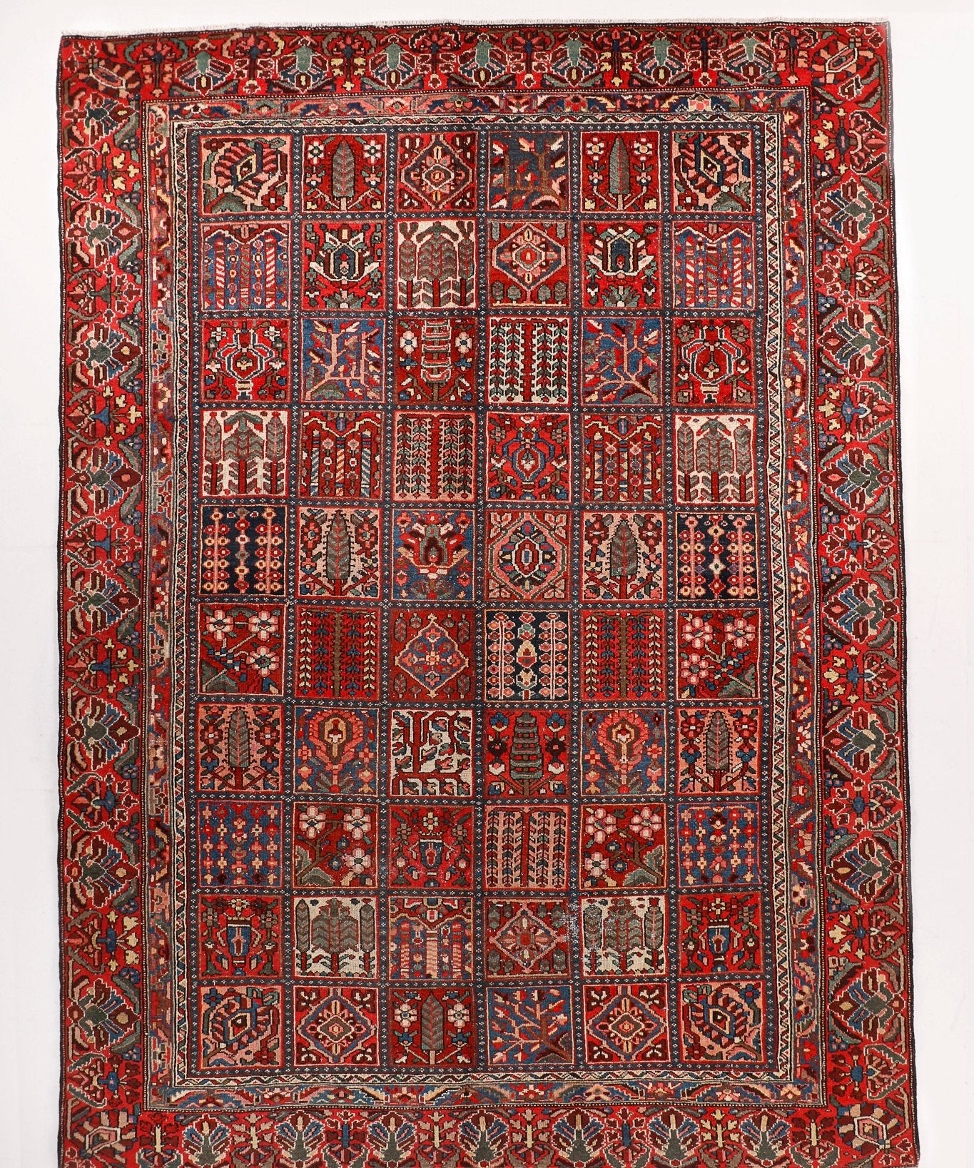 Persian-style area rug with red field and geometric medallion border, multicolor pattern.