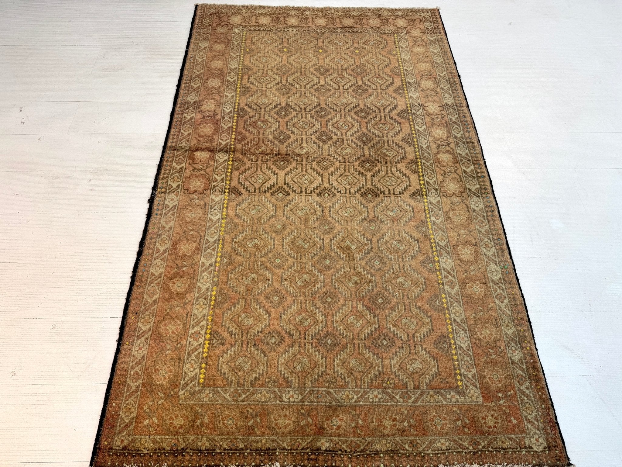 Persian Baluch rug with central geometric panel, tan and bronze field, framed by ornate borders.