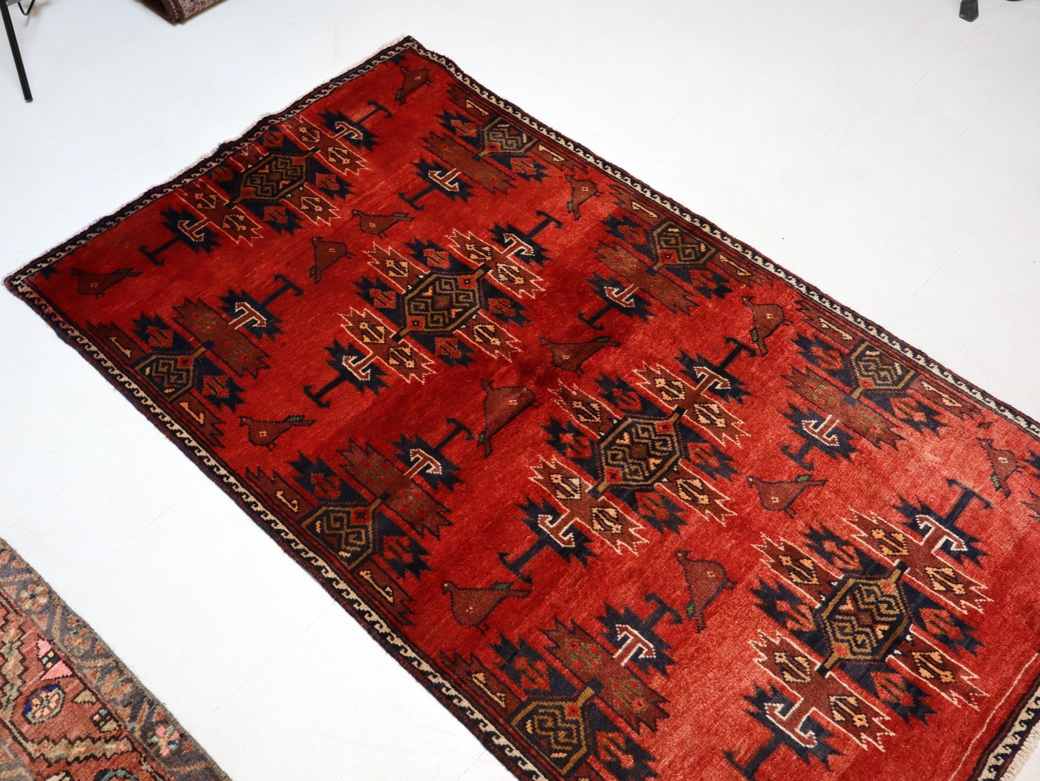 Red rug with bold geometric motifs and dark border, diagonal view on floor