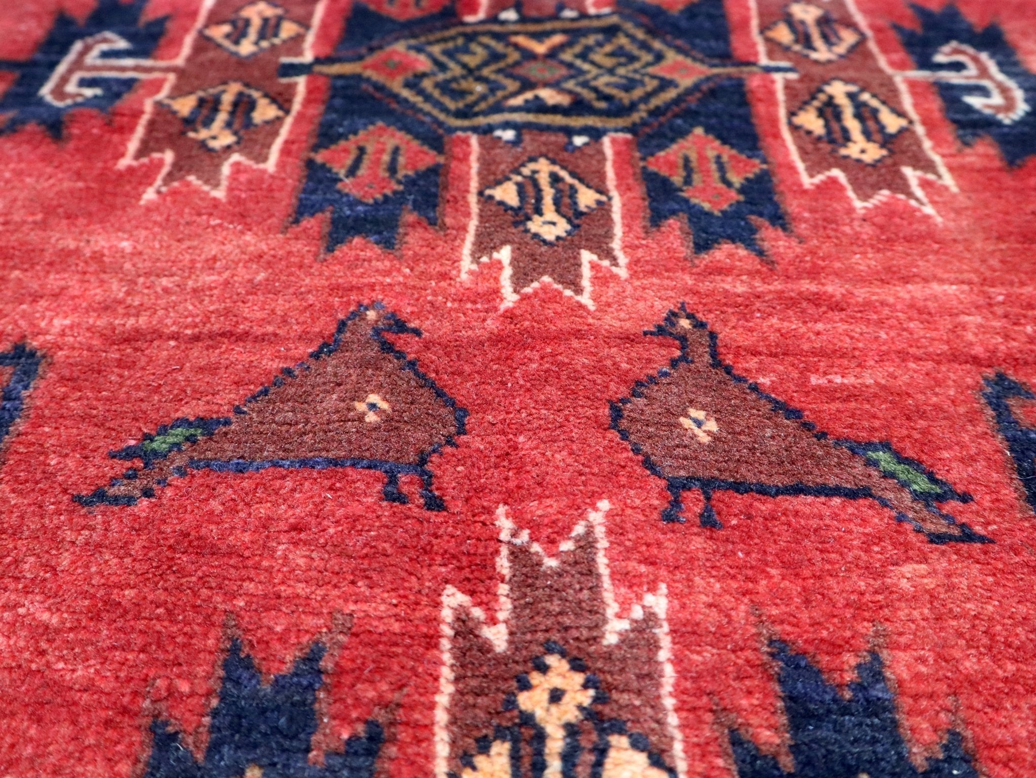 Red rug surface with blue and dark animal motifs and star shapes, close-up