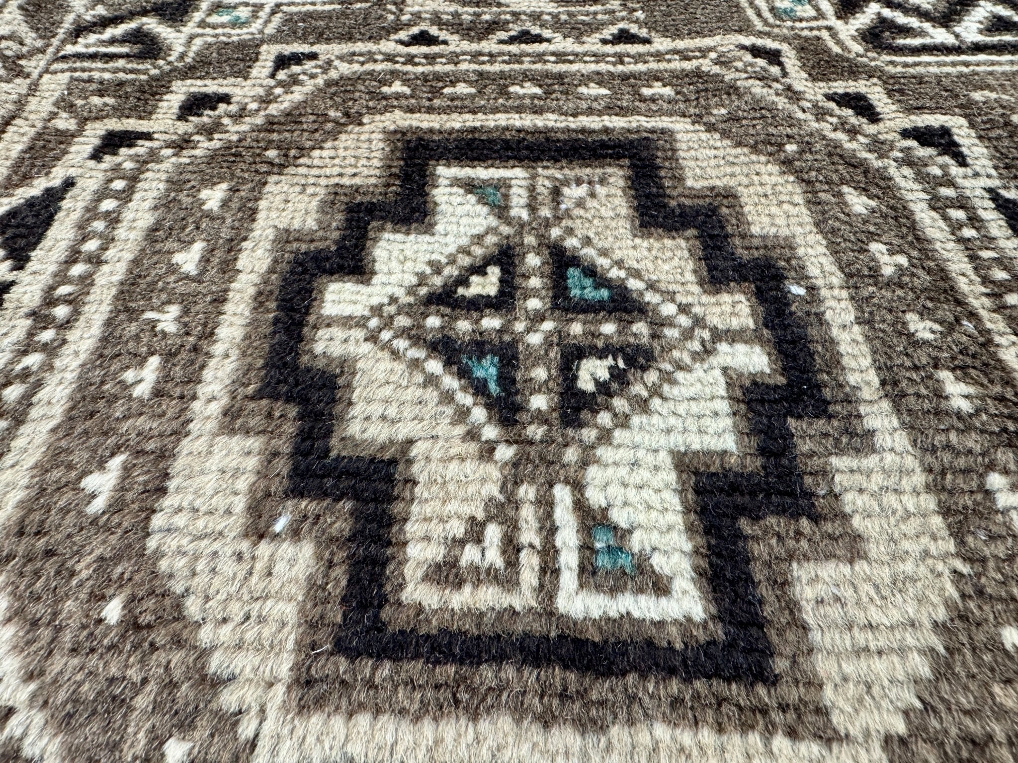Close-up of rug centerpiece with star motif, cream and dark brown tones, teal highlights.