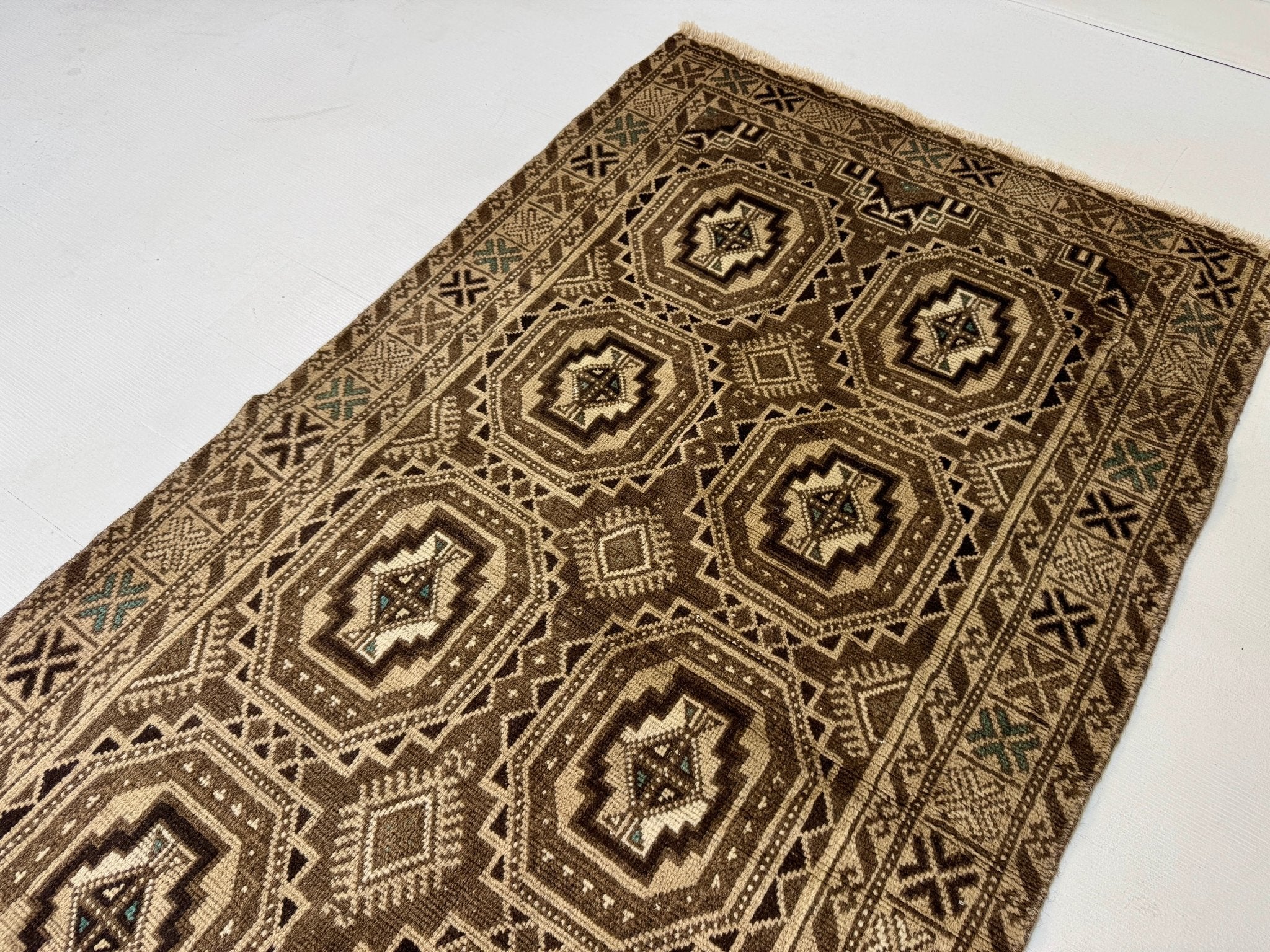 Diagonal view of geometric rug with dark brown octagon medallions and cream lattice border.