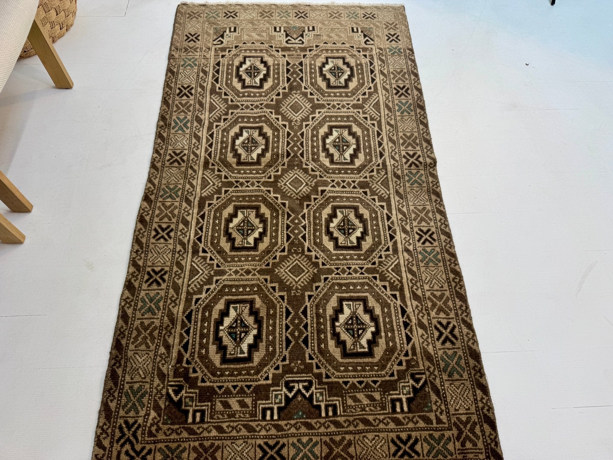 Geometric Persian-style rug with dark brown, cream, and teal diamond and octagon motifs.