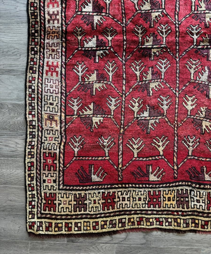 Red Persian rug close-up of tree motifs, cream border strip with black and gold accents