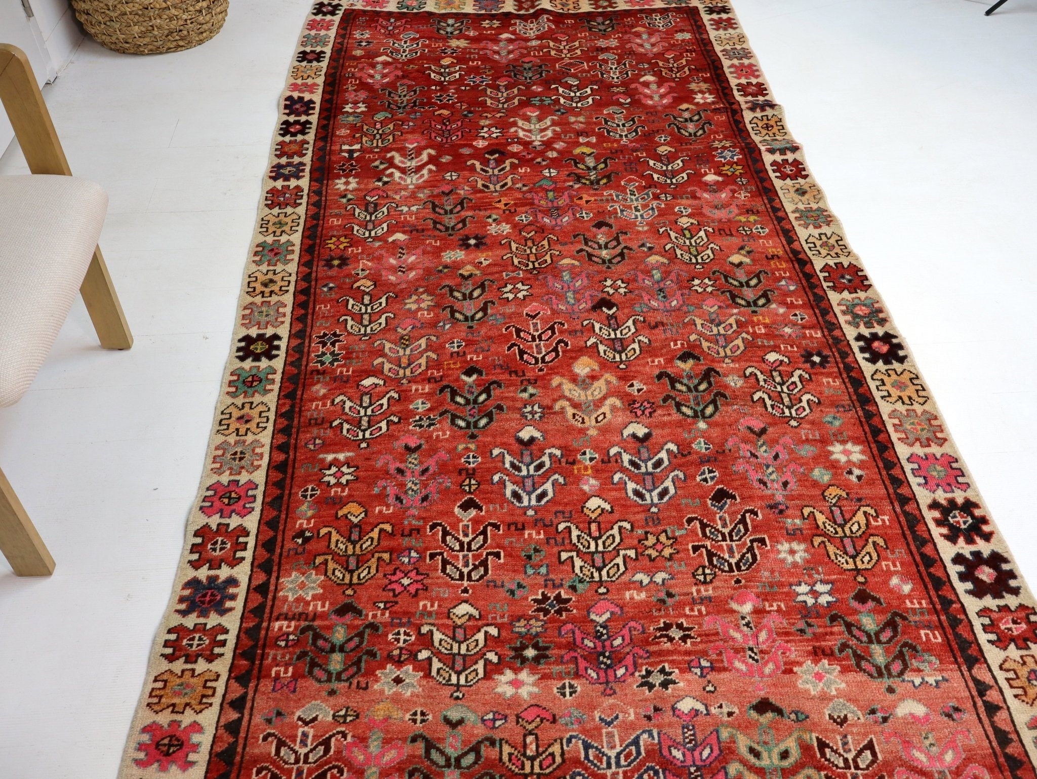 Red patterned rug on the floor with decorative border and allover motifs