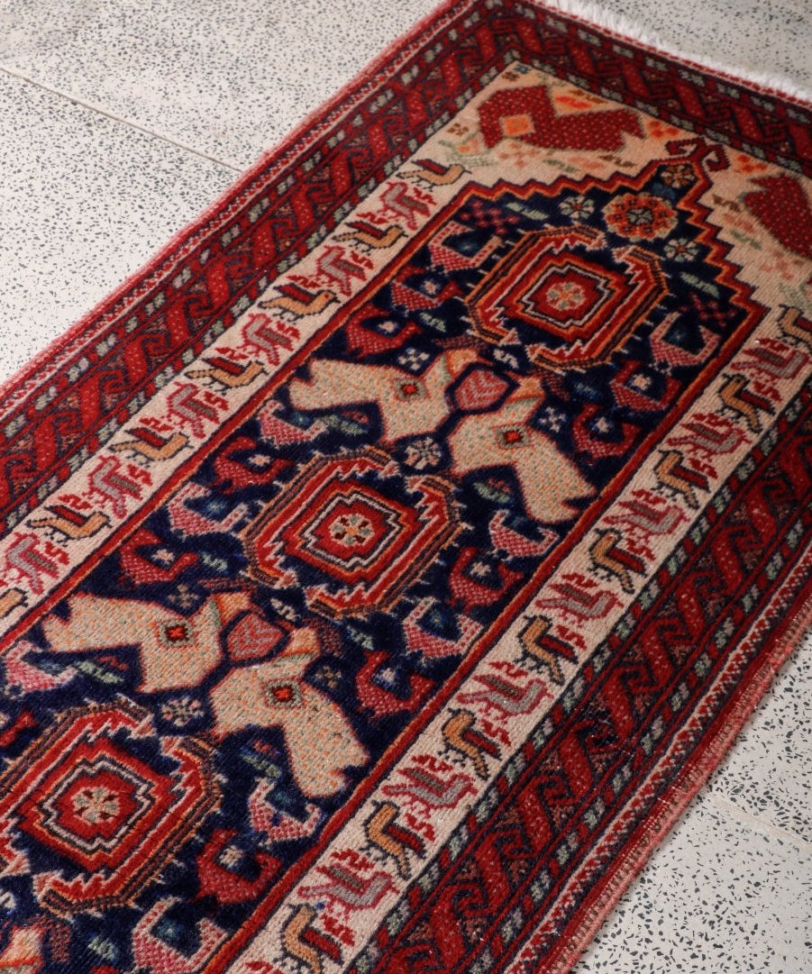 Persian Baluch runner rug close-up of navy and red rosette pattern on cream